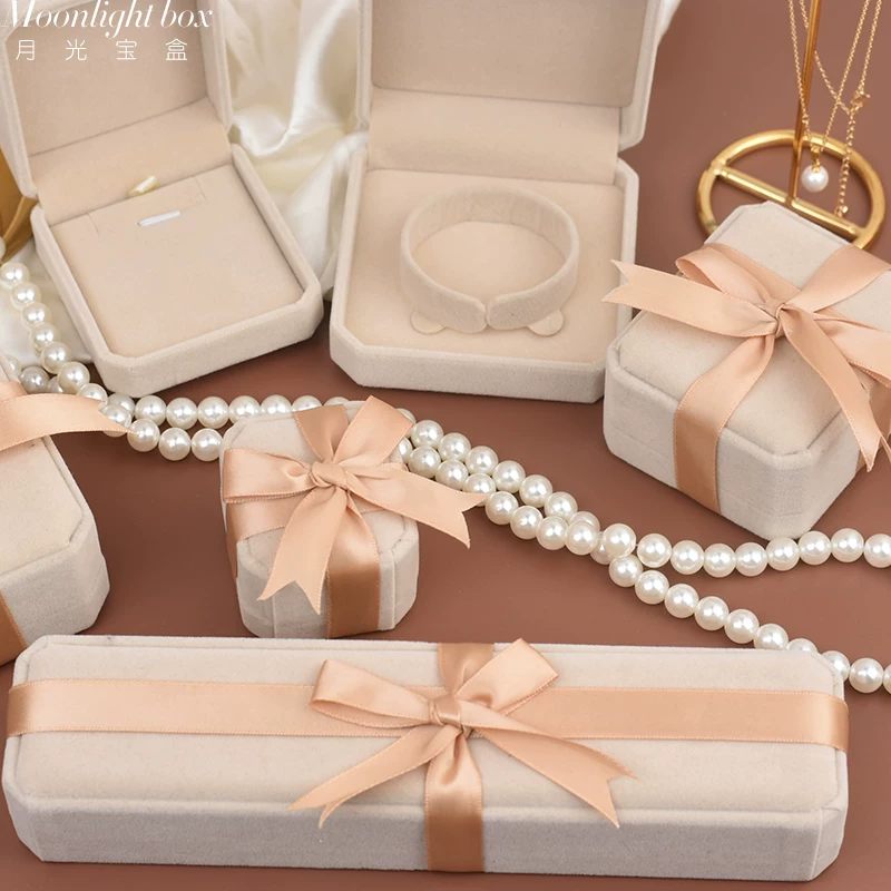 Cream jewelry boxes with peach ribbon bows and pearl details